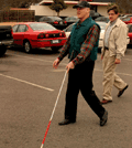 Man with white cane in parking lot