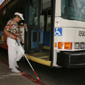 Lady with white cane boards bus