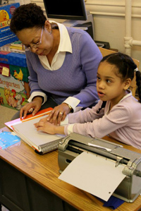 A young girl reads braille with her teacher's help