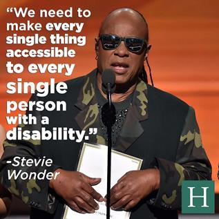 Stevie Wonder holds a brailled card while standing on stage at the Grammys; text reads: We need to make every single thing accessible to every single person with a disability.