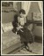 Thumbnail of Photograph of Helen Keller seated on a chaise longue next to a sm...
