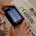 Handheld video magnifier being used to read newspaper