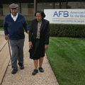 Older gentleman with cane walking with daughter in front of AFB Dallas