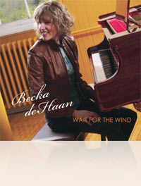 Becka de Haan sitting at the piano, turned around and smiling