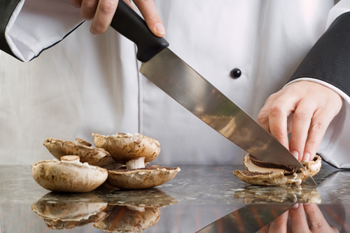 Chef Wearing Black and White Uniform Slicing Brown Mushrooms