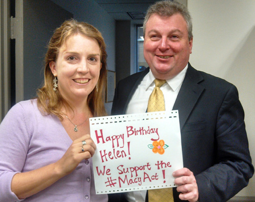 Rebecca and Mark holding a sign that reads: Happy Birthday, Helen! We support the #MacyAct!