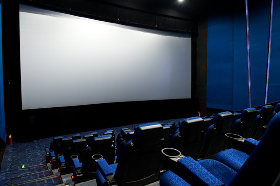 Dark movie theatre interior, screen and chairs.