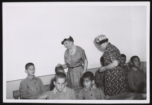 Photograph of Helen Keller and Polly Thomson in a school room with boys who are blind, Jordan May 13, 1952