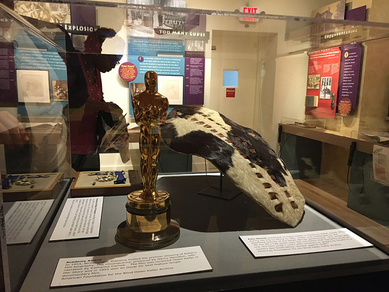 a Zulu shield, Helen Keller's Academy Award and her presidential medal of freedom, on display in a glass case at the APH museum