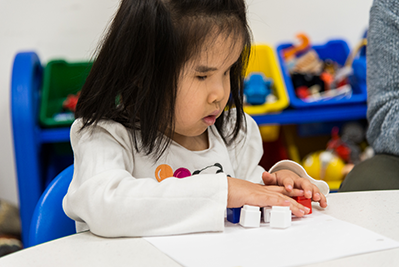 Female elementary student with blocks at school table.