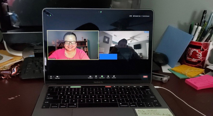 A laptop shows a video Zoom meeting between two coworkers.