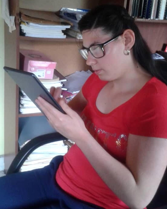 A young Latinx woman uses a tablet in a home office.