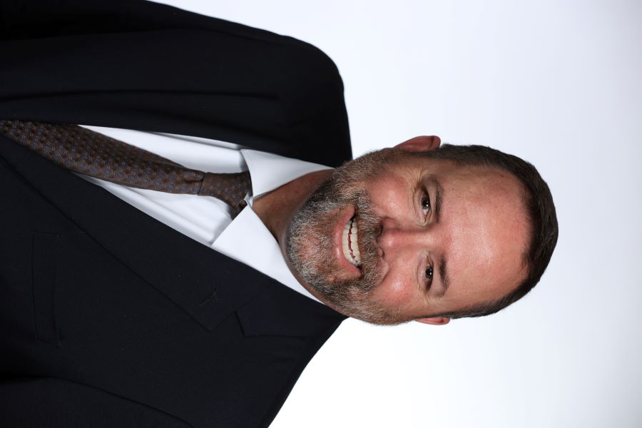 Chris Fendrick headshot. Man wearing shirt and tie, smiling.