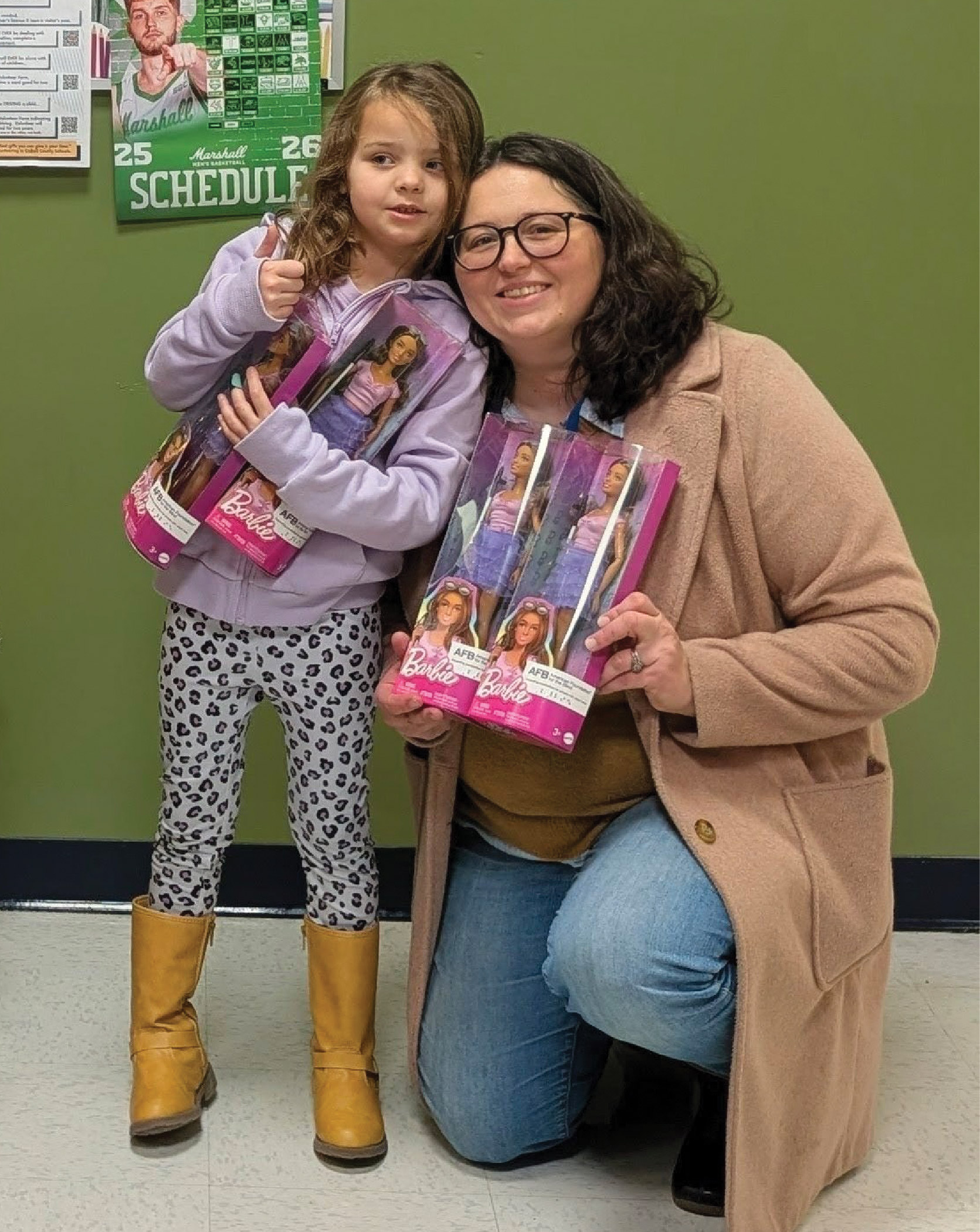A woman and her daughter holding Blind Barbie's. Both smile while the daughter gives a thumbs up.