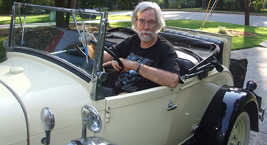 man wearing a Walters 2.8x telescope lens system to drive a replica of an antique car.