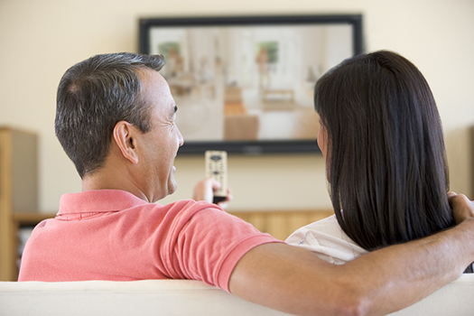 Asian couple smiling while watching TV