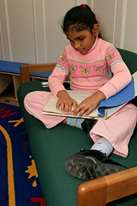 school-aged girl reading braille