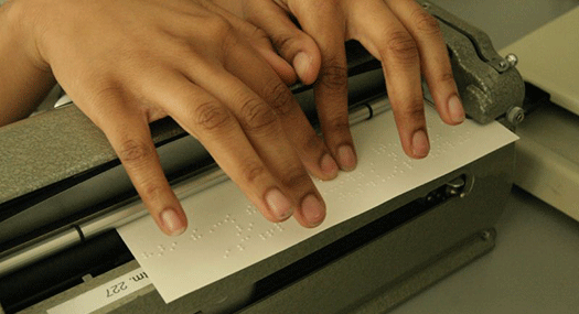 Closeup of student's hands checking the braille she is embossing