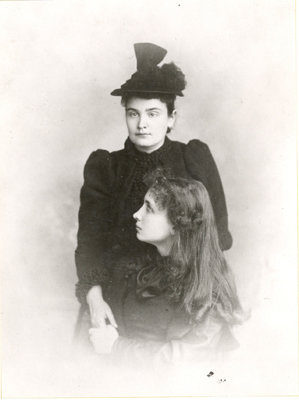 Helen Keller and Anne Sullivan Macy formal portrait. Keller is seated infront of Macy. With her left hand, Keller holds her teacher's right hand, circa 1893