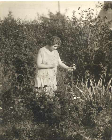Helen Keller holding a flower in her garden