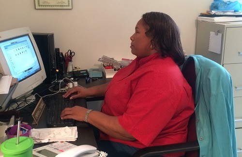 A woman in a red blouse typing on computer
