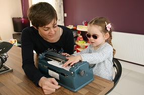Child being taught how to use a braille writer