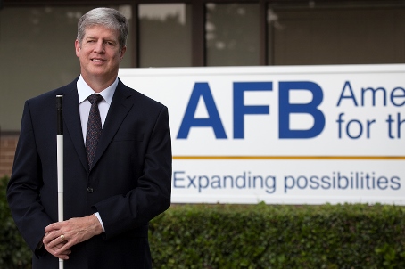 Kirk Adams stand in front of an AFB sign