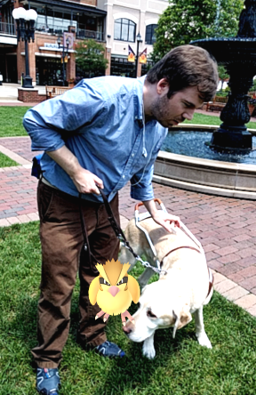 Aaron Preece stands with his guide dog Joel and a Pidgie Pokemon