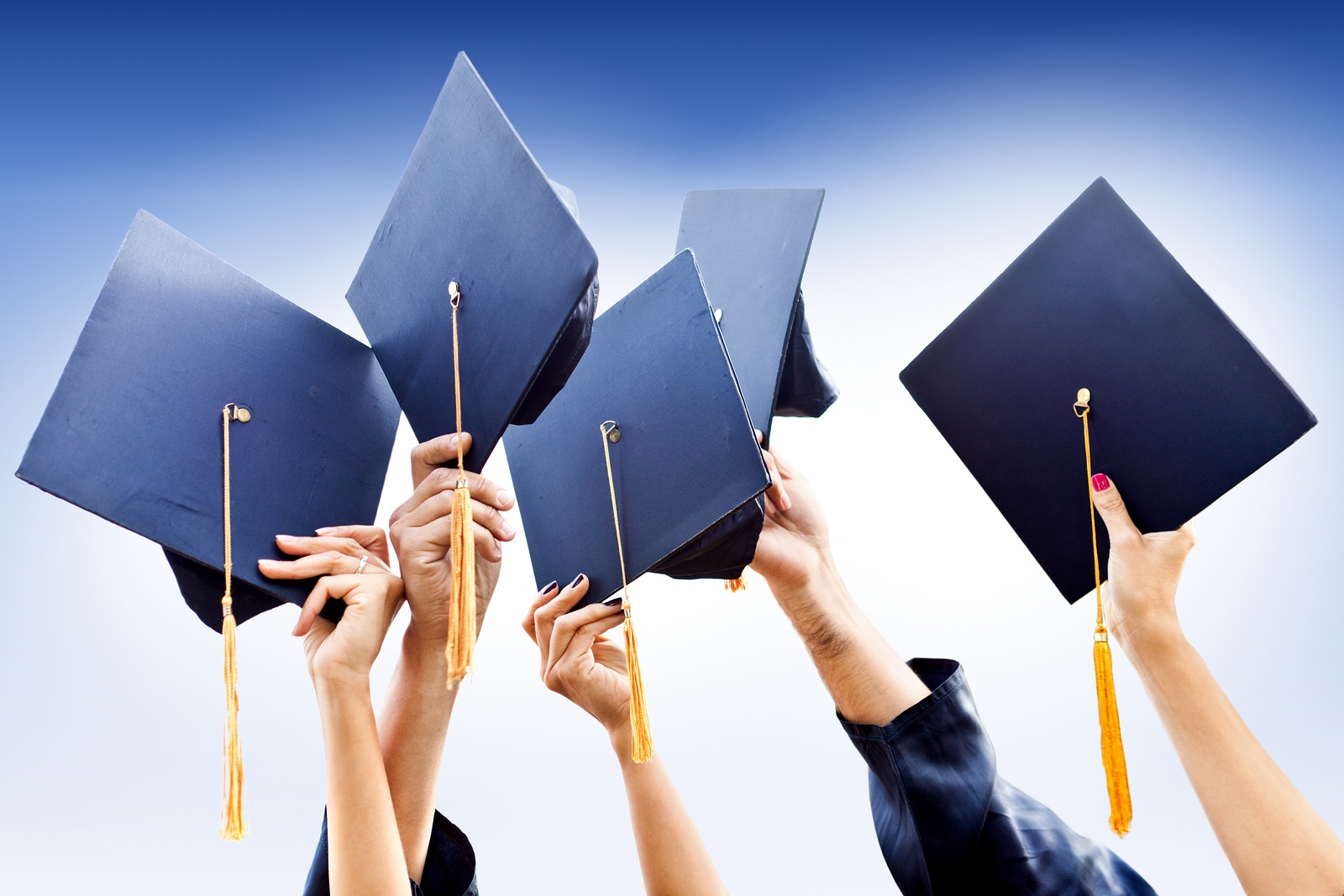 Arms throwing graduation caps into the air