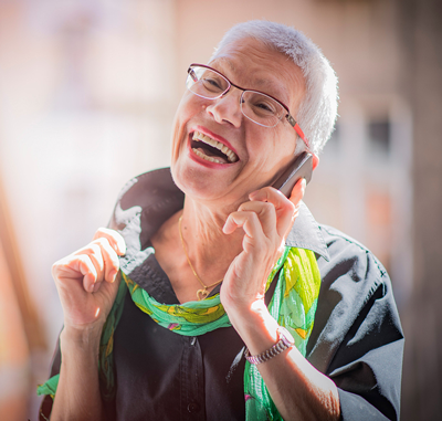 Lovely senior lady having a fun conversation with her friend or a family member over her cell phone