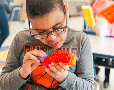 a student focuses on snapping together colorful building blocks