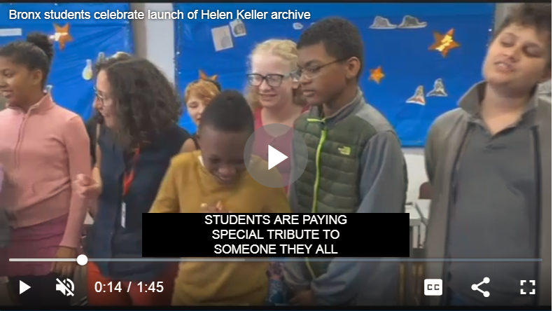 Video still of students at the New York Institute of Special Education singing happy birthday to Helen Keller. 