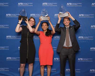 Two women and a man holding up their awards