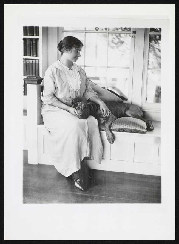 Black and white photo of Helen Keller sitting with a dog