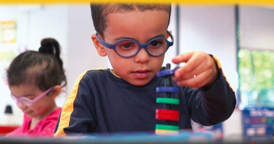 Young boy in classroom playing with stackable rings.