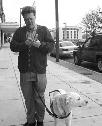 Figure 2. Photo of man with dog guide dialing the Audiovox 9500.