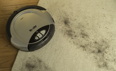 Photo of the Roomba clearing a clean swath in a muddy carpet.