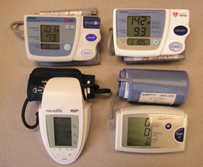 Photo of four blood pressure monitors showing large-print displays.