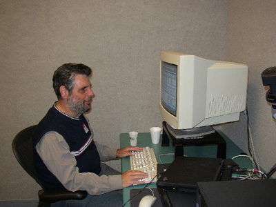 Photo of a man sitting in front of a computer monitor with hands on a keyboard.