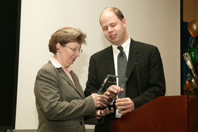 Mary Ann Cummins Prager receiving a Lucite plaque from Jim Denham.
