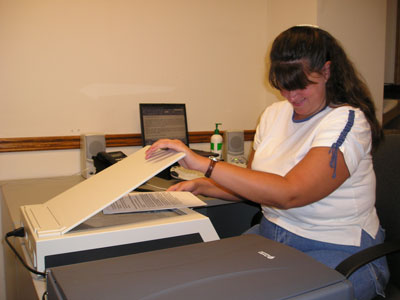 Photo of a woman placing a page on the ScannaR's scanning surface.