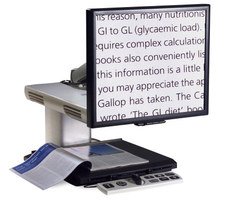 The SmartView Xtend showing magnified text from a book on its reading table. The Simple Remote from Module 1 is positioned in front of the reading table.