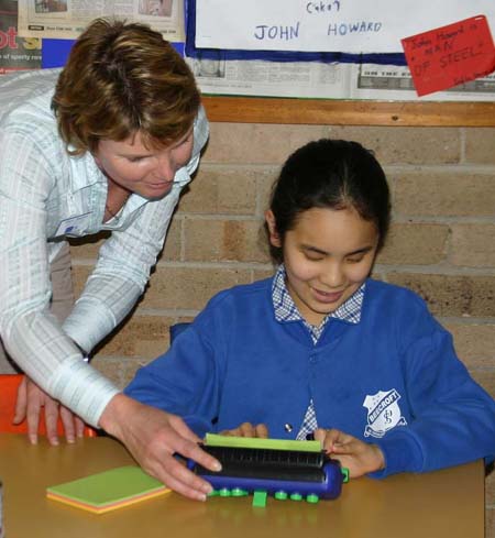 A teacher observing a student using the small Jot a Dot braille writer.
