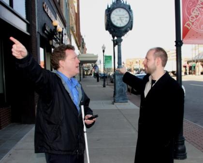 The author, white cane and GPS in hand, argues with a friend about which way to go.