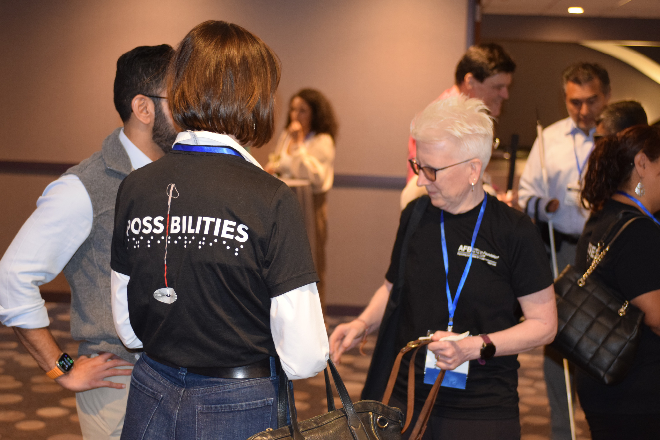 Attendees wearing their Possibilities t-shirts in a reception hall.