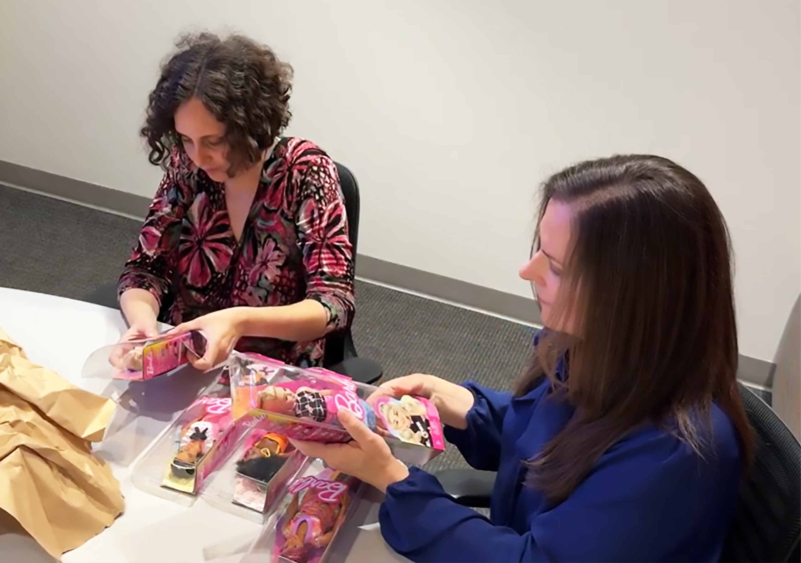 Two women unboxing Barbie dolls.